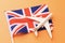 Great Britain flag and toy plane on orange background, concept of flying to the United Kingdom