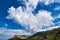 Great dynamic clouds in beautiful blue sky over hills and slope at daytime. Typical Greek landscape in spring.