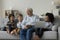 Great-grandpa and great-grandsons sit on couch holding diverse devices