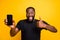 Great promo choose. Portrait of funny afro american man hold smartphone show thumb up sign advise select device suggest