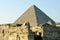 The great pyramid of Giza with a wall of stones and rocks and a side profile of the Sphinx