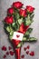 Great red roses bouquet with loop and greeting card with heart, top view. Love symbol