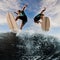 Great view of two energetic men jumping on a wakeboard over a splashing wave