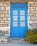 Greece, blue door on traditional island house stone wall and marigold flower