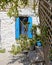 Greece, blue window shutters on traditional Mykonos house white washed stone wall