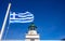 Greece. Kea island lighthouse. Greek flag waving on blue sky background