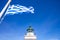 Greece. Kea island lighthouse. Greek flag waving on blue sky background