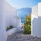 Greece, Santorini island, Oia - white architecture of a narrow street with flowers, steps lead to the sea. Greek Islands,