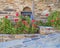 Greece, stone wall with blue window and flowers