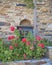 Greece, stone wall with blue window and flowers