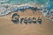 Greece written in the sand on a beach. Greek tourism and vacation background