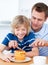 Greedy boy and his father putting honey on waffles