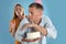 Greedy man hiding birthday cake from woman on turquoise background