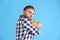 Greedy young man hiding bowl with chips on light blue background