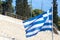 Greek flag waiving in the air in Athens, Greece. The stairs and seats of the Panathenaic stadium can be seen in the background.