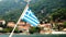 Greek flag waving over ship at Greek old town in greens