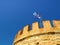 The greek flag on The White Tower of Thessaloniki on the shore of The Aegean Sea, Thessaloniki, Greece