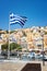 Greek flags, boats and colorful neoclassical houses in harbor town of Symi Symi Island, Greece