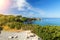 Greek holidays - Waves break on rocky shore. Coast and beach resort village. Road along a rocky cliff. Tourist beach