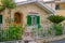 Greek house facade with green wooden shutters on windows