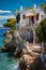 Greek house resort perched on rocks near the sea, set against the stunning backdrop of the Mediterranean.