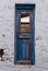 Greek Island, Cyclades. Blue wooden close broken vintage door, weathered stonewall