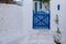 Greek Island, Cyclades. Blue wooden fence entrance gate close,  whitewashed stonewall plant at yard.l