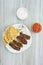 Greek Kebabs, pita bread ,chopped onion in plate and yogurt and tomato sauce in bowls