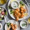 Greek lunch - chicken kebabs, greek salad, tzatziki, flatbreads and white wine. On a light background