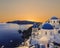 The Greek Orthodox Church on the background waters of the Aegean sea in Oia at sunset. The Island Of Santorin