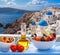 Greek salad against famous church in Oia village, Santorini island in Greece