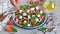 Greek salad in a bowl. Female hand seasoning vegetable and feta cheese salad with herbs. Concept of preparing Vegetable Salad step