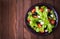 Greek salad (lettuce, tomatoes, feta cheese, cucumbers, black olives) on dark wooden background top view