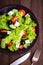 Greek salad (lettuce, tomatoes, feta cheese, cucumbers, black olives) on dark wooden background top view