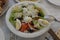 Greek salad with vegetables, cheese, olives and eggs on a white plate