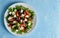 Greek salad on white plate on bright blue table, top view, copy space