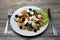 Greek salad on a white plate with fork and knife on a wooden table. Can be used as a photo for restaurant menus, bistro. European,