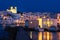 Greek whitewashed houses and church by harbour watersfront after sunset, Naoussa, Paros island, Greece