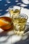 Greek wine in 2 glasses, fresh ripe orange served in garden in sun lights