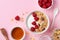 Greek yogurt in bowl with raspberries, honey and muesli on pink table top view. Healthy diet breakfast