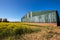 Green agricultural barn building on farm with rapeseed crop field