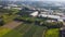 Green agricultural fields and greenhouses near town. Clip. Top view of beautiful flat fields with greenhouses in summer