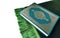 Green Al-Quran on green rug isolated white background