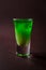 Green alcoholic shot glass with absent, irish cream, liquor on e