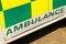 Green AMBULANCE sign on side of NHS vehicle.