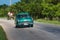 Green american classic car drive on the road in the countryside Santa Clara Cuba.