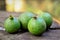 Green American genipa fruits on wooden stump table