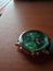 Green analog wrist watch on wooden table with soft light