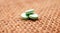 green antidepressant pills on small jute bag background
