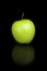 Green apple on a black reflective background